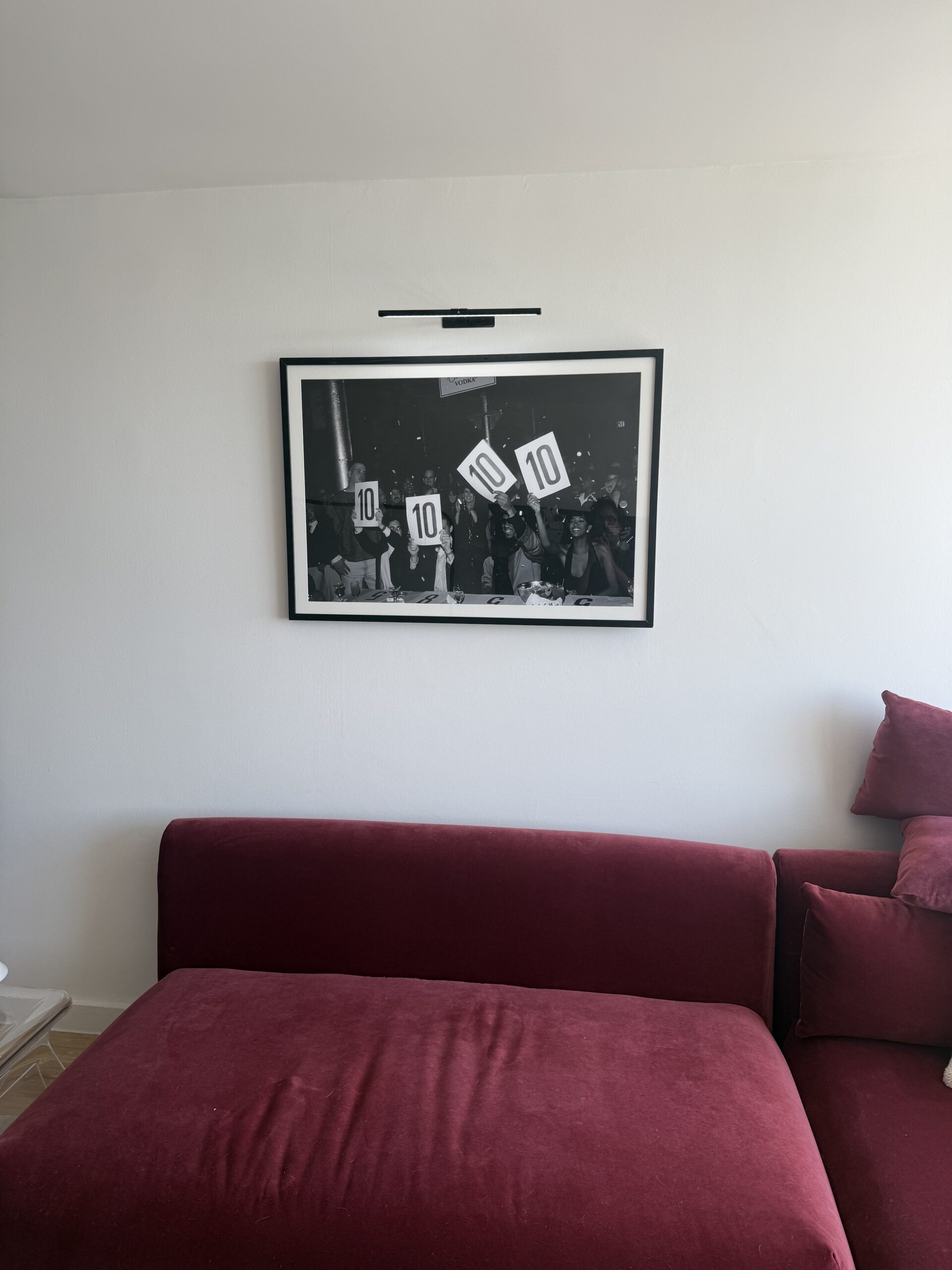 Framed black and white photo gallery wall next to red sofa NYC