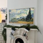 Samsung Frame TV displaying Van Gogh art mounted above white fireplace mantle, NYC brownstone with Christmas decor