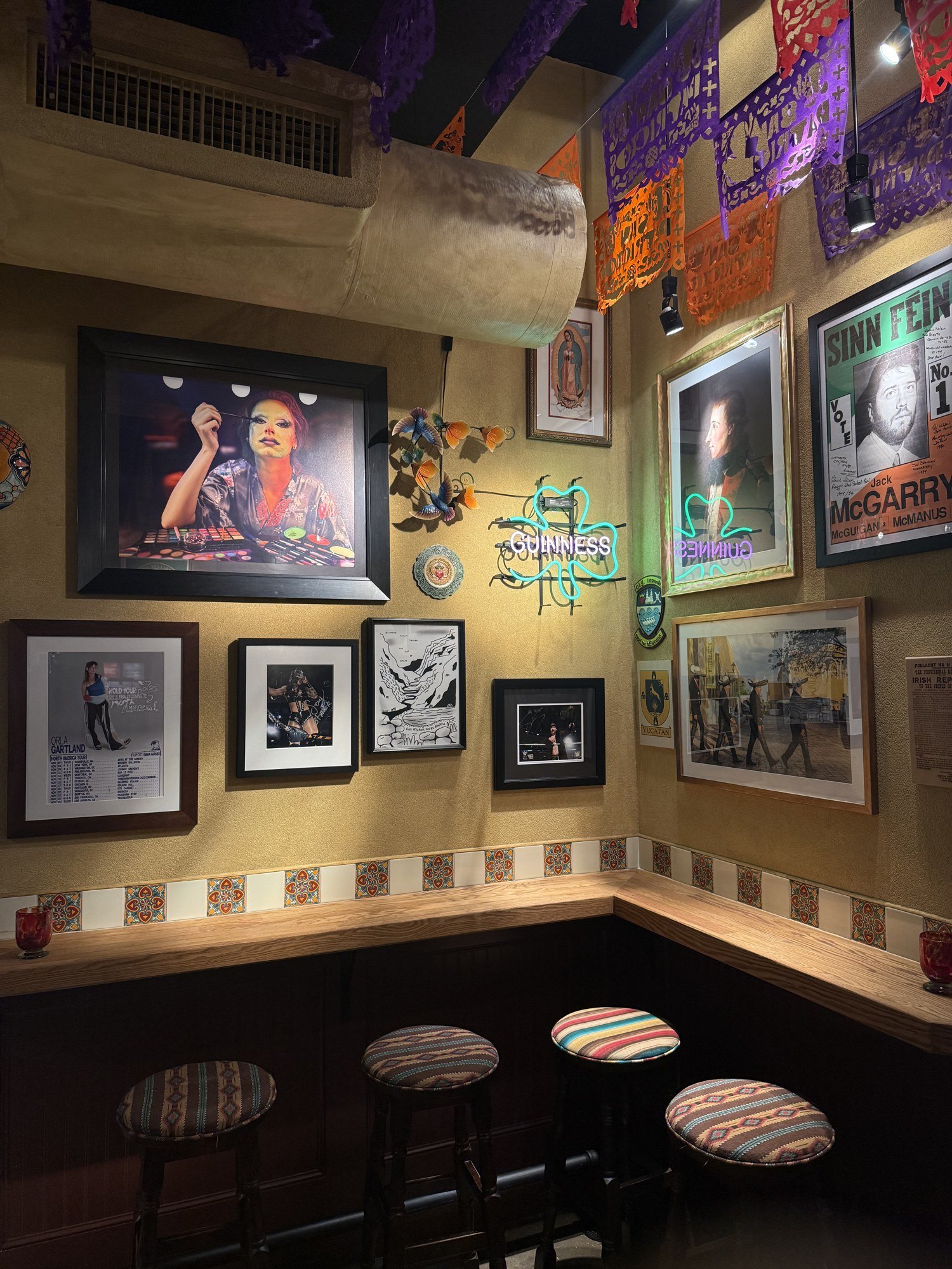 Colorful gallery wall of framed pieces installed in a NYC bar