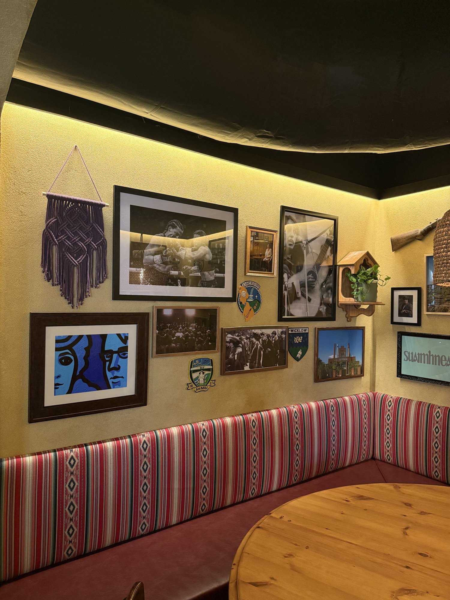 Gallery wall and hanging textiles installed above a bar banquette
