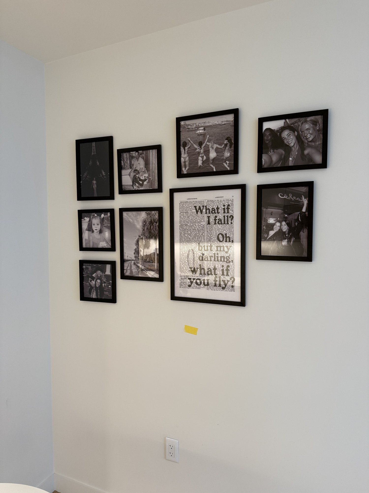 Black and white photo gallery wall arranged around a quote print