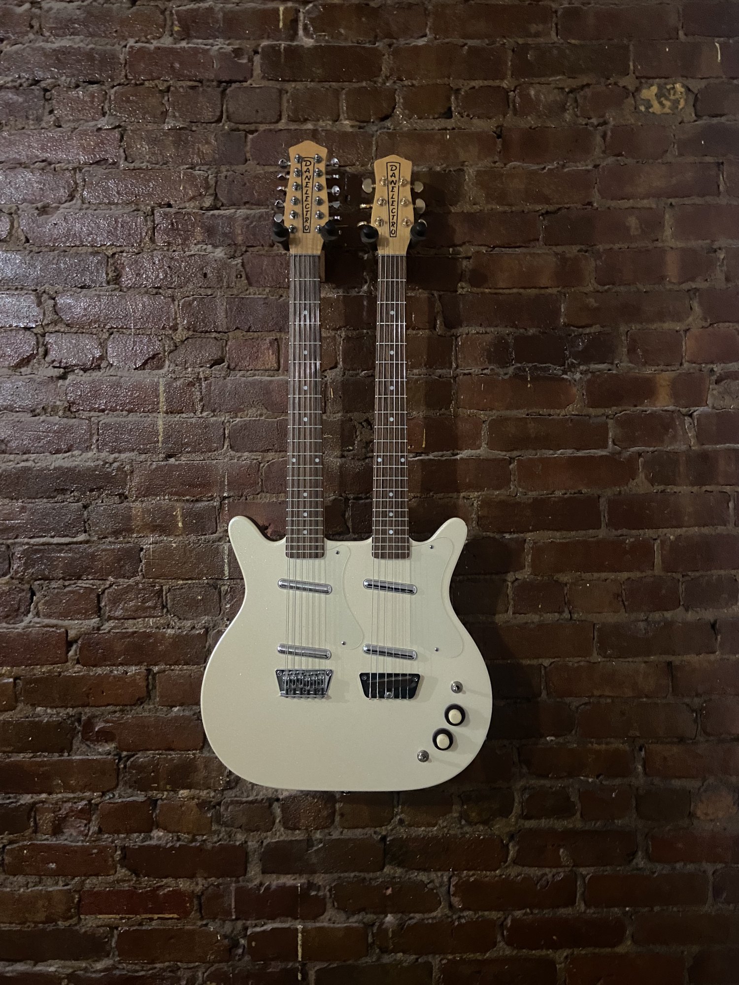 Double-neck guitar wall-mounted on exposed brick
