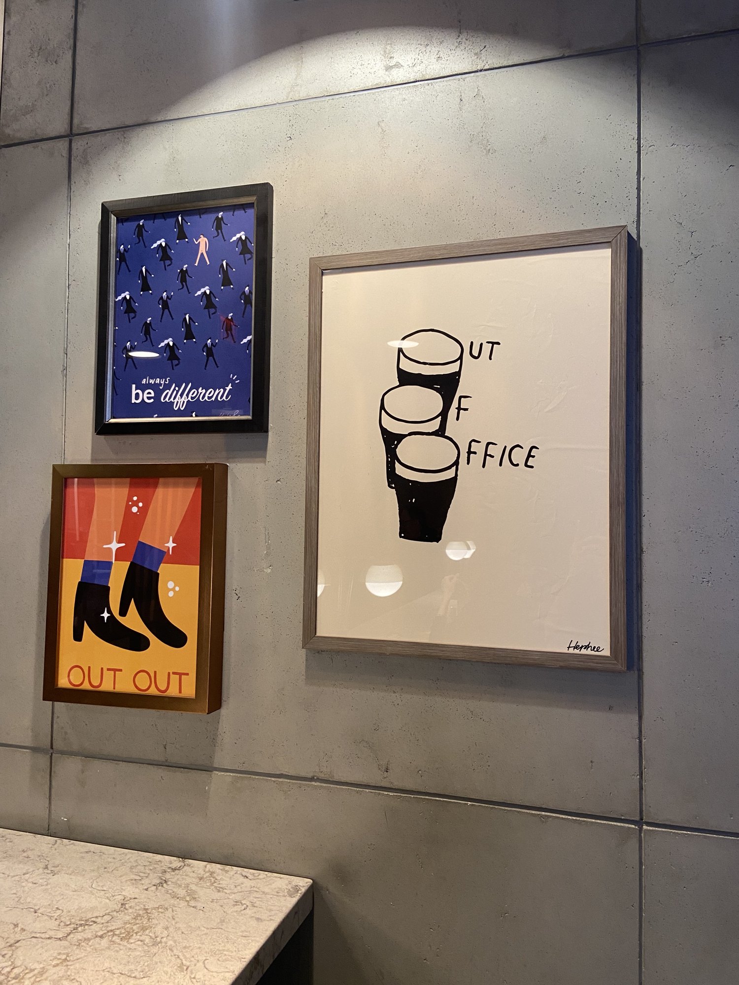 Framed art mounted on a concrete wall at a NYC bar