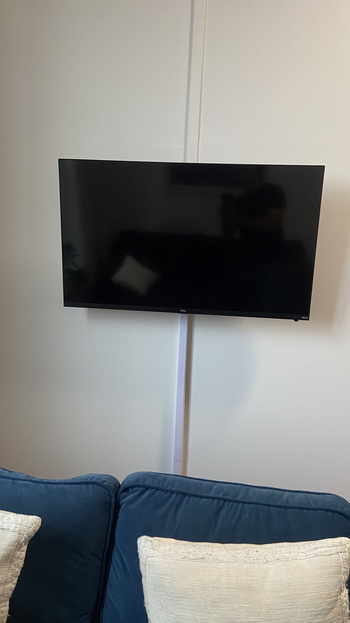 TV wall-mounted with hidden wires above a living room sofa