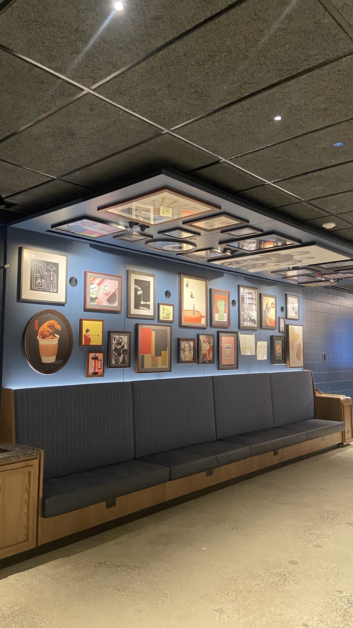 Wall of framed photos installed above banquette seating in a NYC restaurant